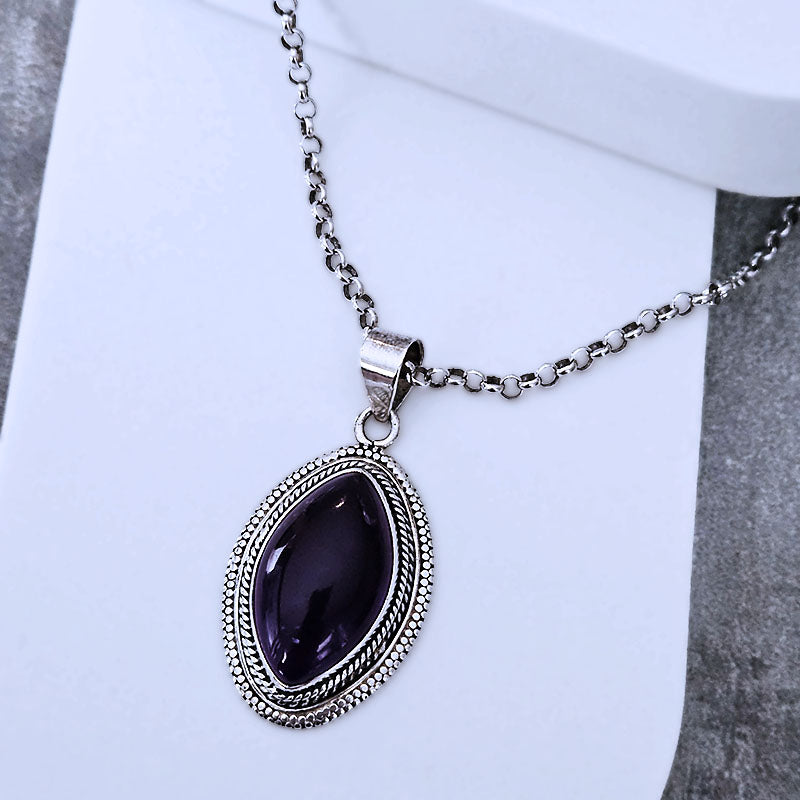 Silver necklace with a purple pendant on a white background