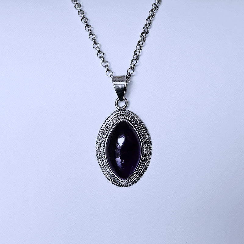 Necklace with a pendant featuring a dark stone on a light purple background