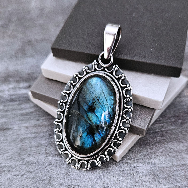 Silver pendant with blue labradorite gemstone on a gray surface