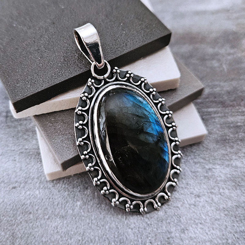 Silver pendant with a blue gemstone on a textured surface