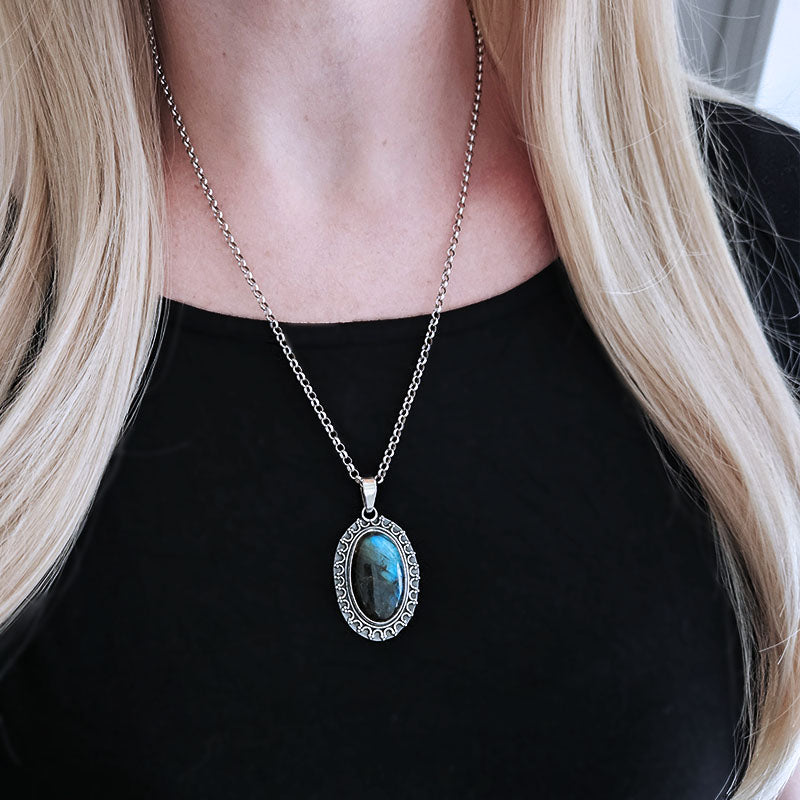 Necklace with a blue pendant worn by a person with long blonde hair.