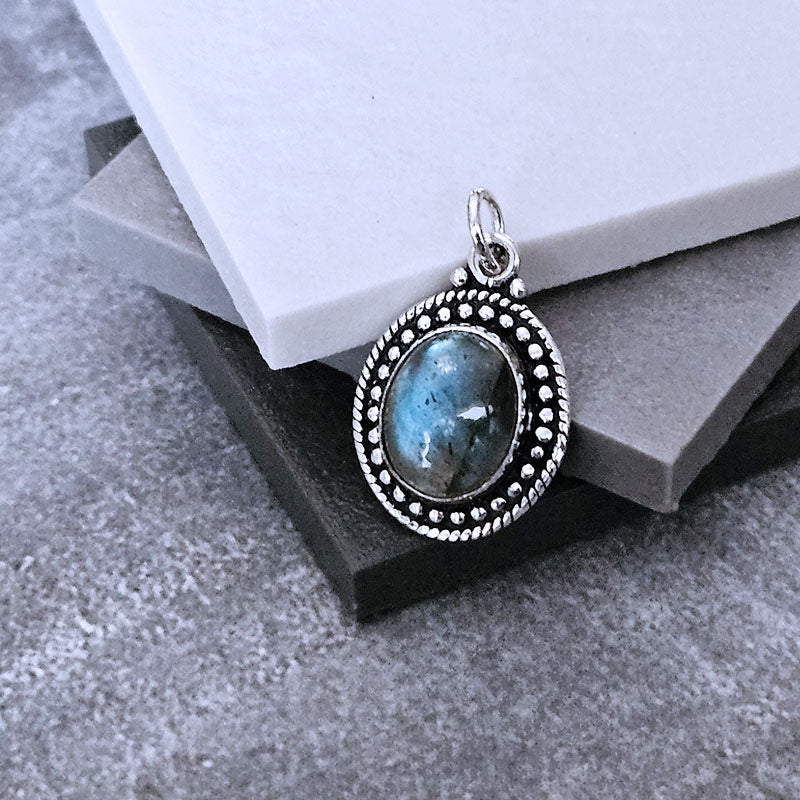 Silver pendant with a blue stone on a textured surface