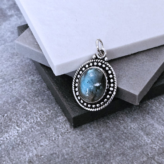 Silver pendant with a blue stone on a textured surface