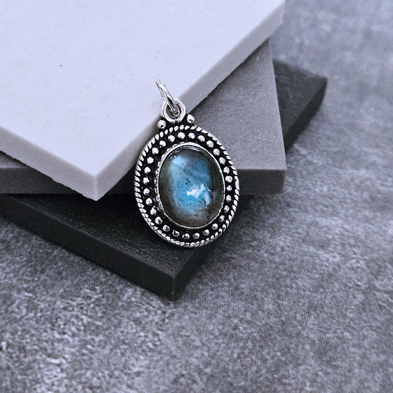 Silver pendant with a blue gemstone on a gray surface