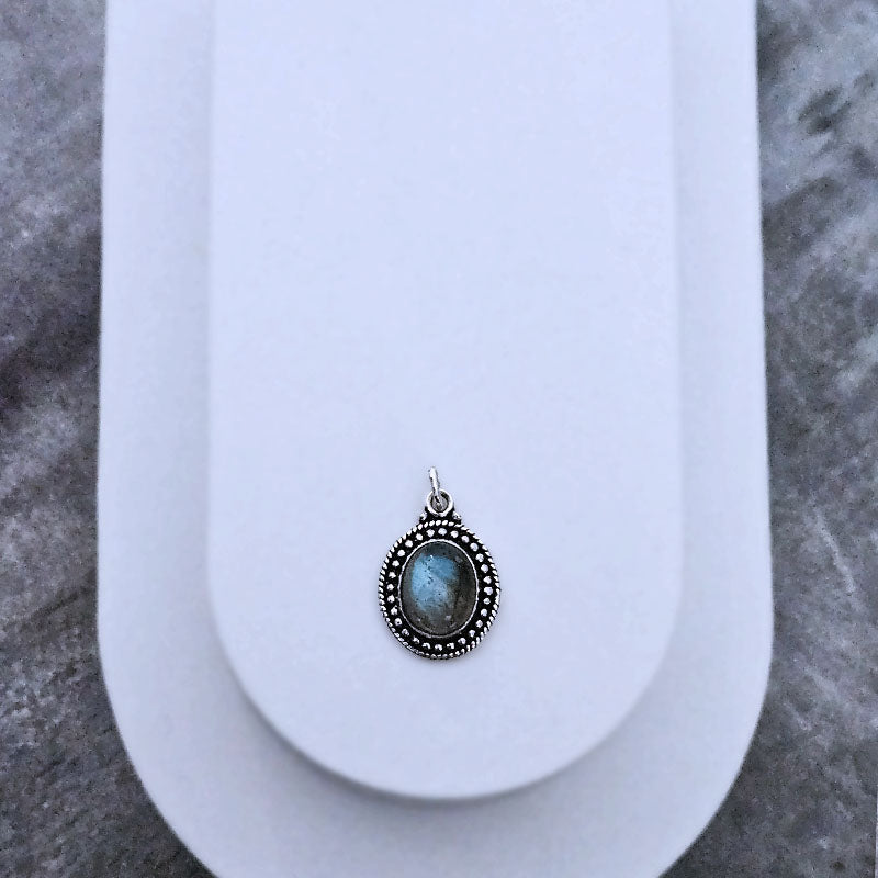 Silver pendant with a blue stone on a white surface