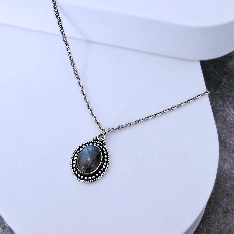 Necklace with a pendant featuring a blue stone on a white surface