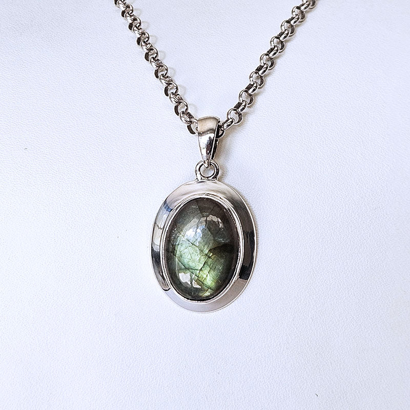 A silver oval pendant necklace featuring a green iridescent labradorite stone, displayed on a clean white background.