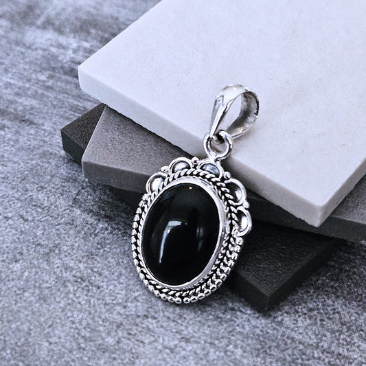 Silver pendant with a black stone on a gray surface