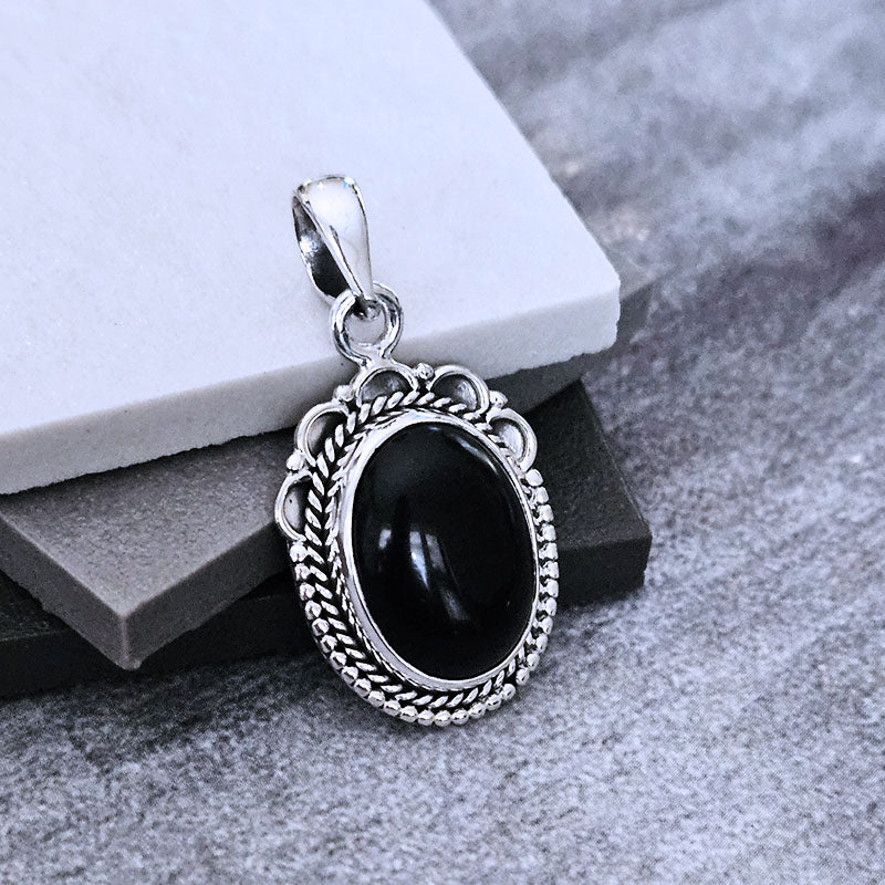Silver pendant with a black stone on a gray surface
