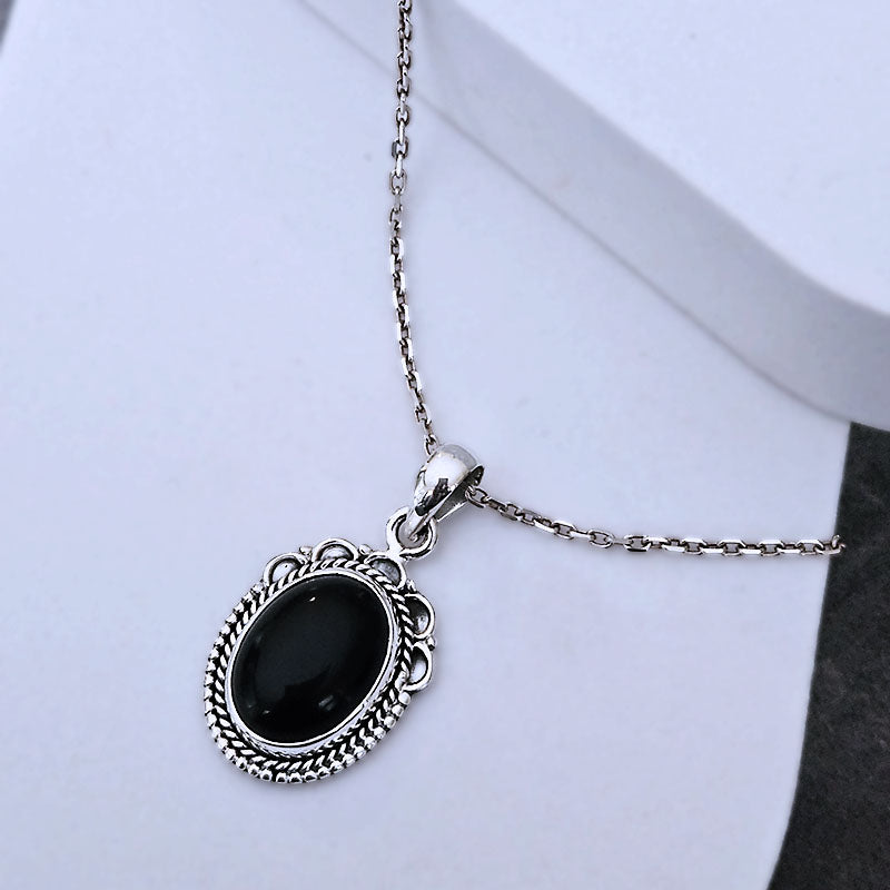 Silver necklace with a black pendant on a white background