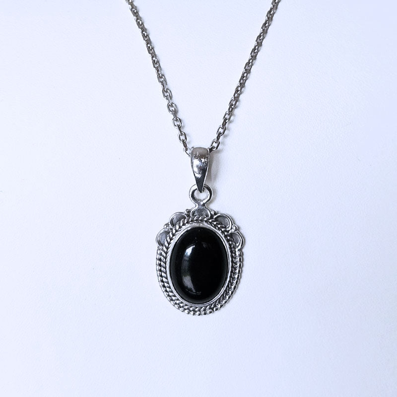 Silver necklace with a black pendant on a white background
