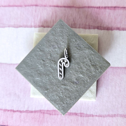 Silver candy cane charm on a gray card with a pink and white striped background