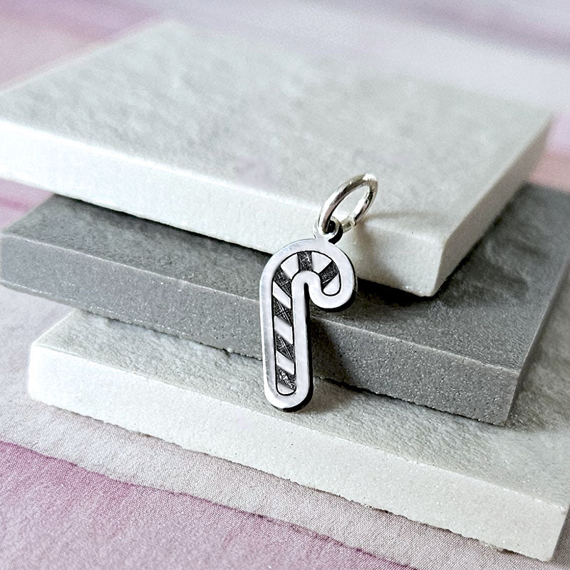 Silver candy cane charm on a stack of gray stone slabs