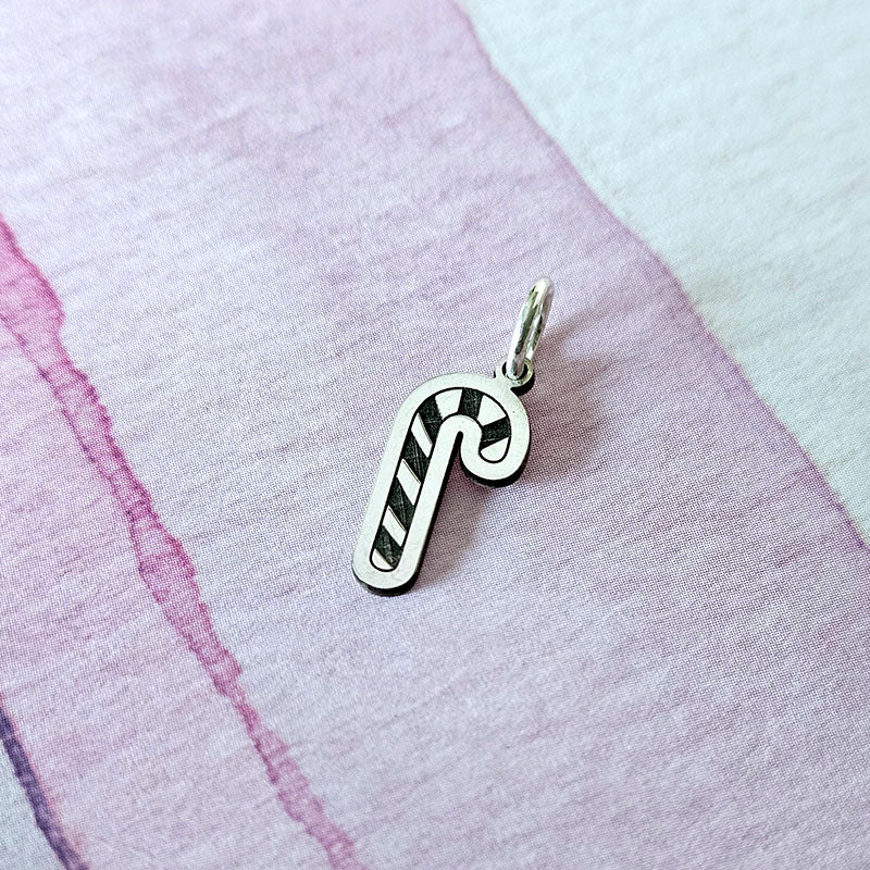 Silver candy cane-shaped pendant on a textured fabric background