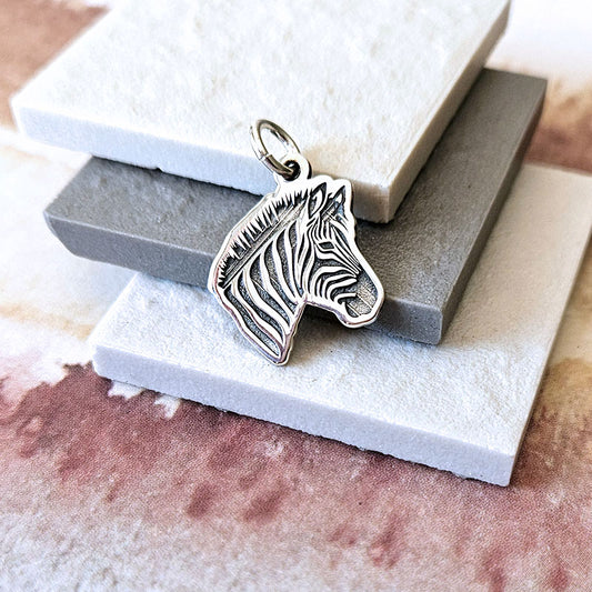 Silver zebra head pendant on a textured surface
