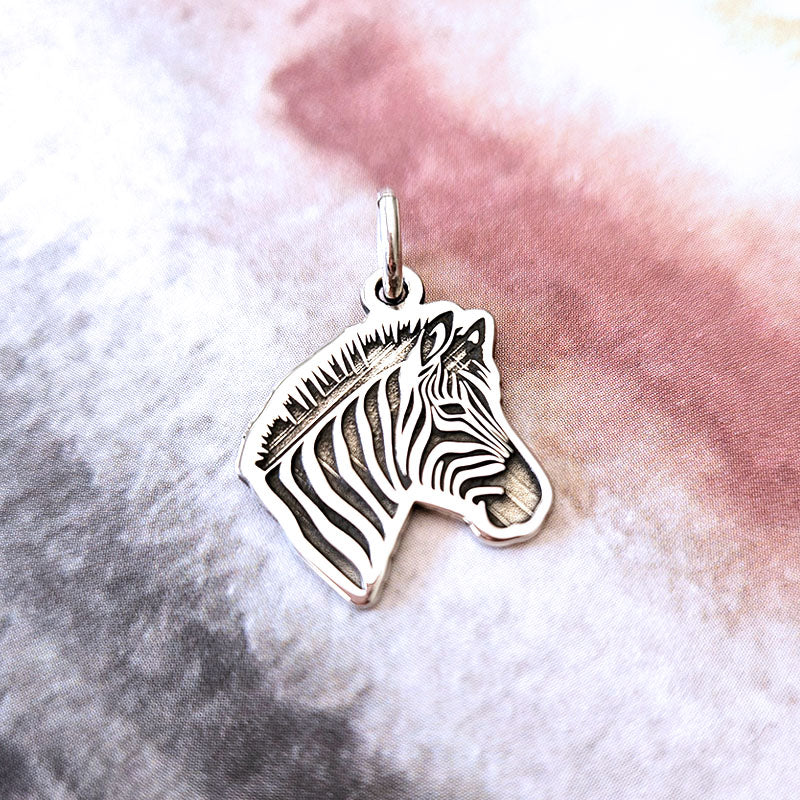 Silver zebra pendant on a textured pink and gray background