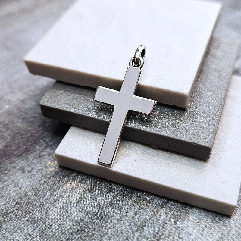 Silver cross pendant on a textured stone surface