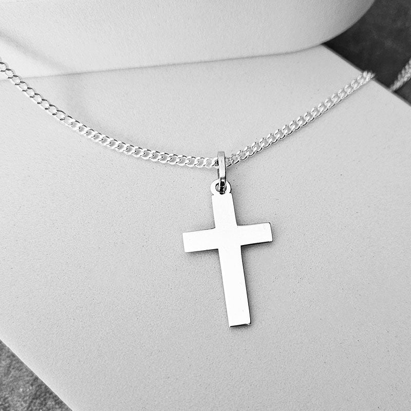 Silver cross necklace on a mannequin with a neutral background