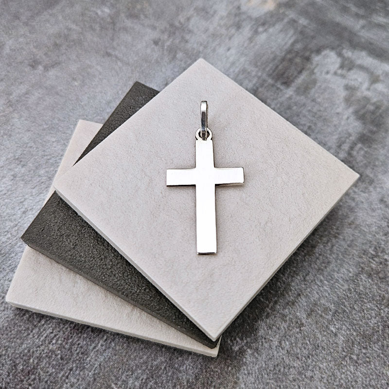 Silver cross pendant on a stack of gray and beige cards