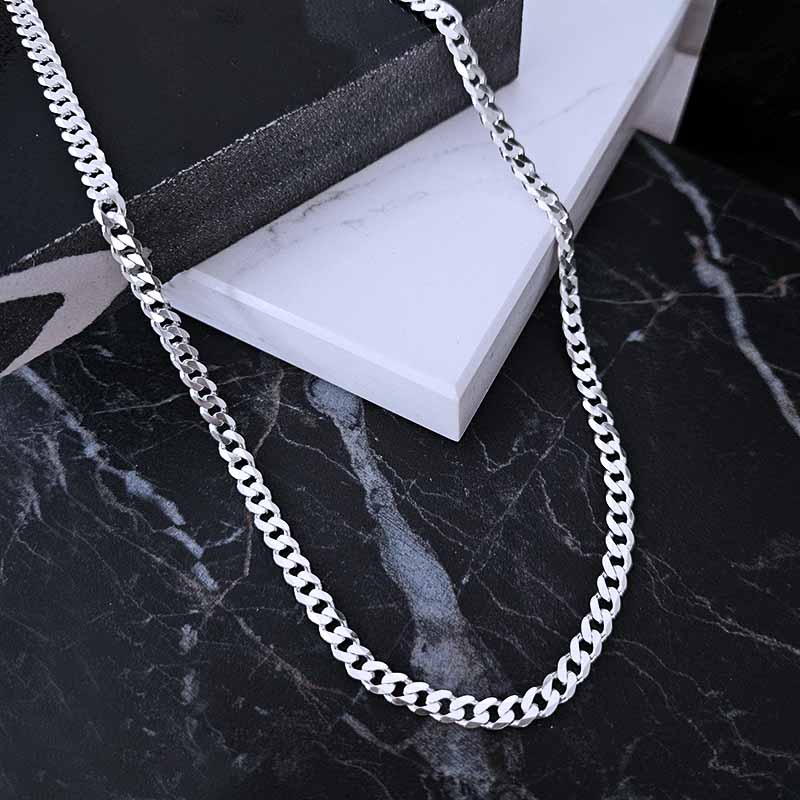 Sterling silver curb link chain on a marble surface