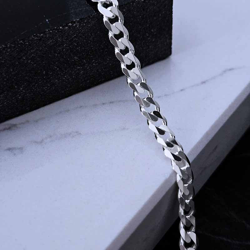 close up of a sterling silver curb chain with a white and black background
