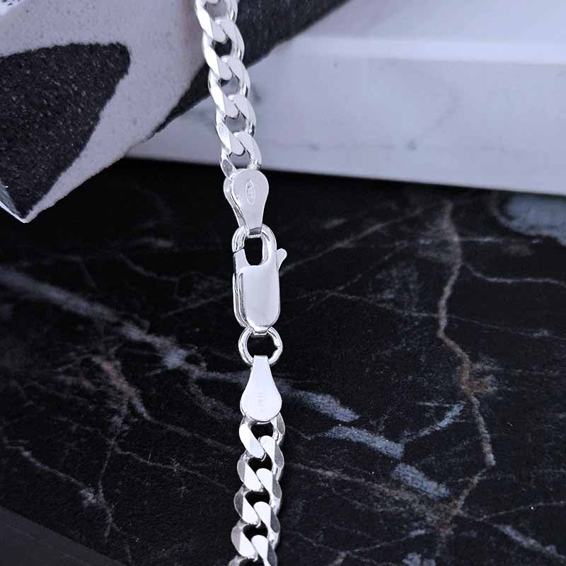 Italian clasp of a thick silver chain on a dark surface