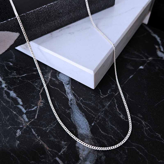 Sterling Silver curb chain - 1,2mm thickness on a black marble surface
