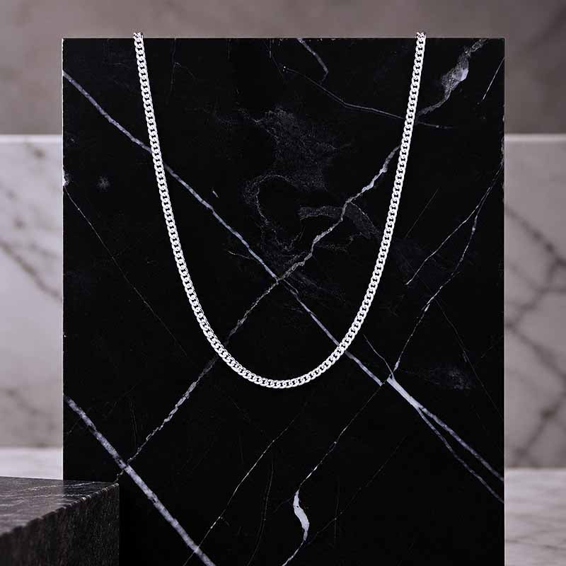 Silver curb chain on a black marble surface
