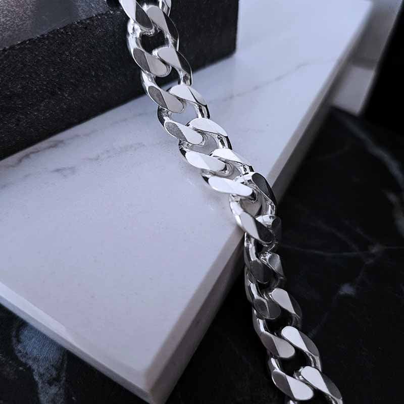 close up image of a silver men's chain on a marble surface