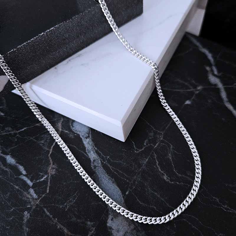 Sterling Silver Curb Chain lying on a black and white marble surface