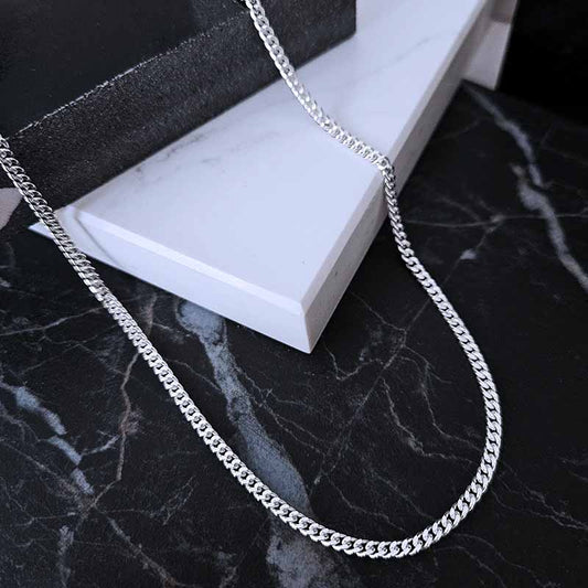 Sterling Silver Curb Chain lying on a black and white marble surface