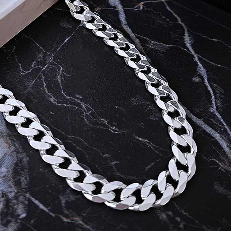 Sterling silver curb link chain on a black marble surface
