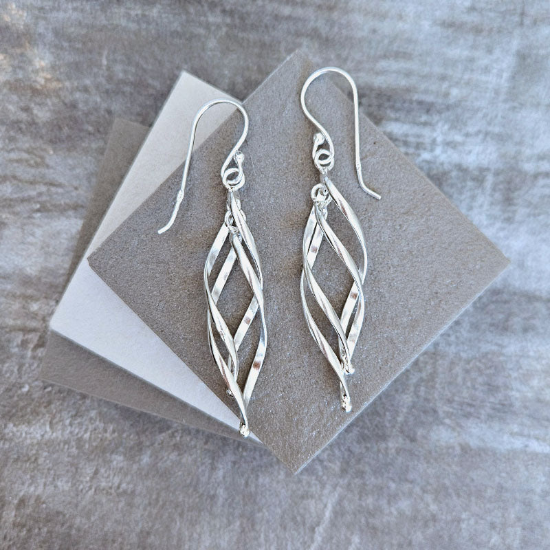 Silver earrings on a gray stone surface