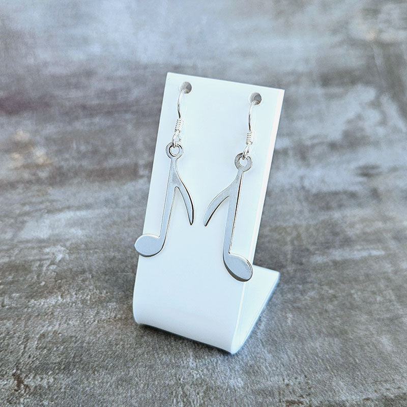 Silver earrings on a white stand against a gray background