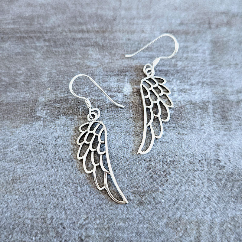 Silver angel wing earrings on a textured gray background