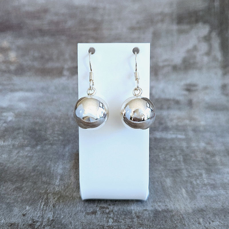 Silver sphere earrings on a white card against a gray background