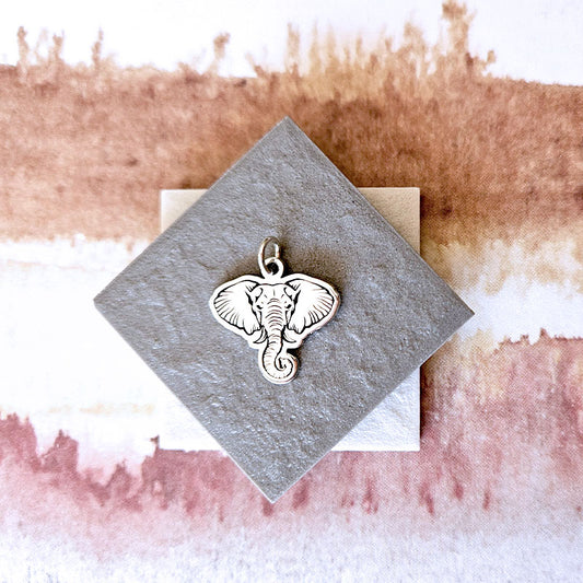 Silver elephant pendant on a textured card with a watercolor background