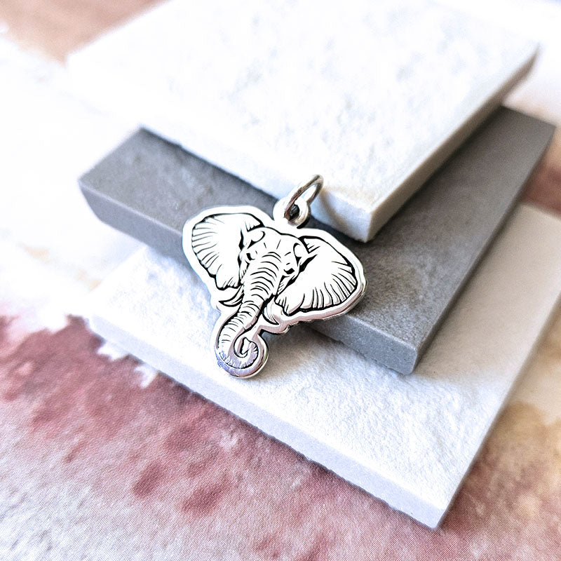 Silver elephant pendant on a white stone surface