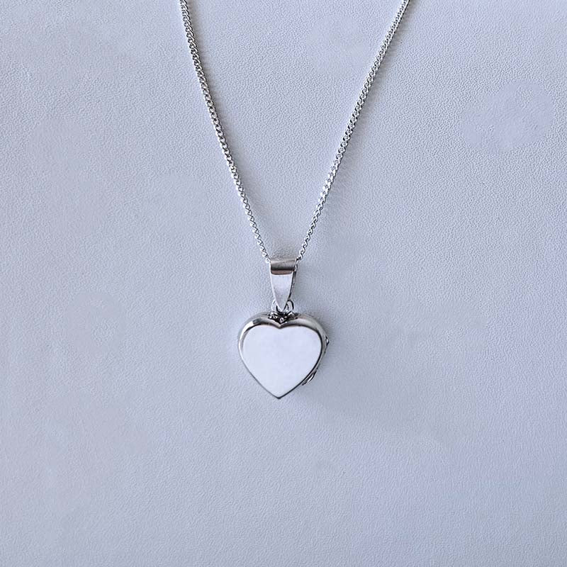 Heart-shaped silver pendant on a light gray background