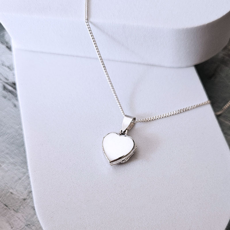 Silver heart-shaped locket on a white surface