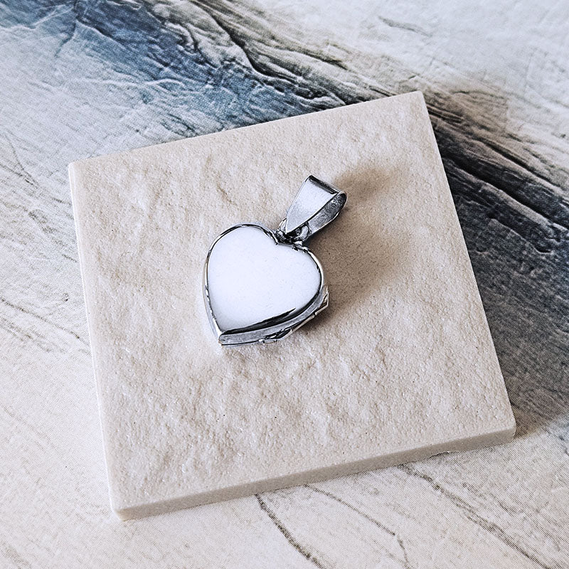 Heart-shaped silver pendant on a marble surface