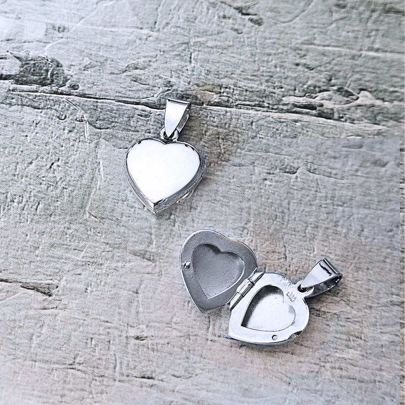Two silver heart-shaped pendants on a textured wooden surface