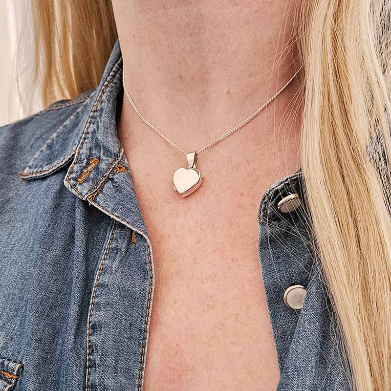 Heart-shaped pendant necklace worn by a person with denim jacket