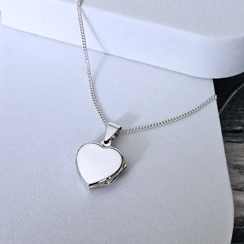 Heart-shaped silver locket on a chain against a white background