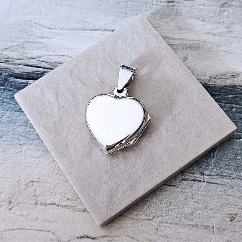 Silver heart-shaped pendant on a textured stone surface
