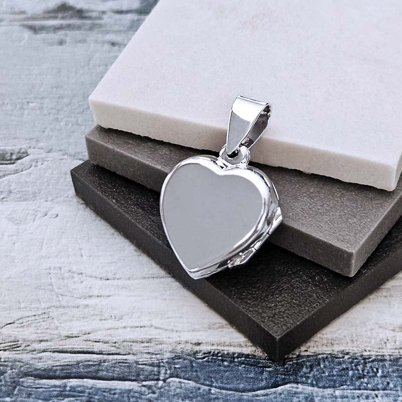 Heart-shaped silver pendant on a textured surface