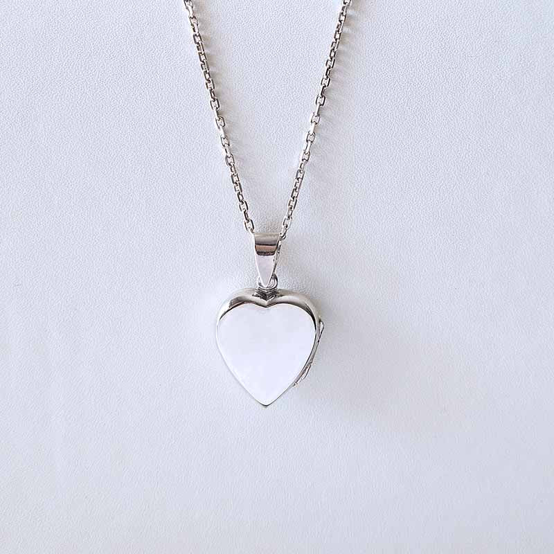 Heart-shaped silver pendant on a light gray background
