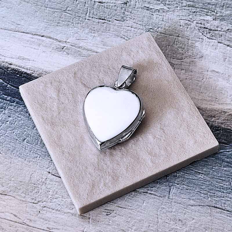 Heart-shaped silver locket on a textured stone surface