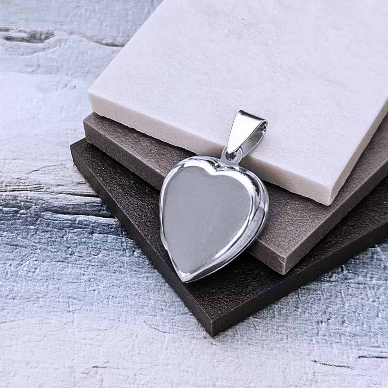 Heart-shaped silver pendant on a textured surface