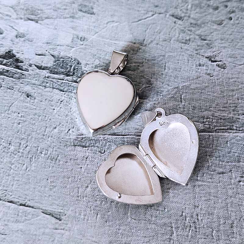 Heart-shaped silver locket on a textured gray surface